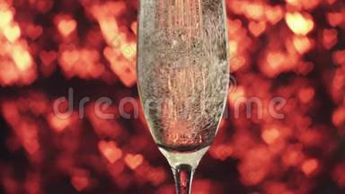 香槟被倒入一个红色背景上的玻璃杯中，里面有许多心，靠近。